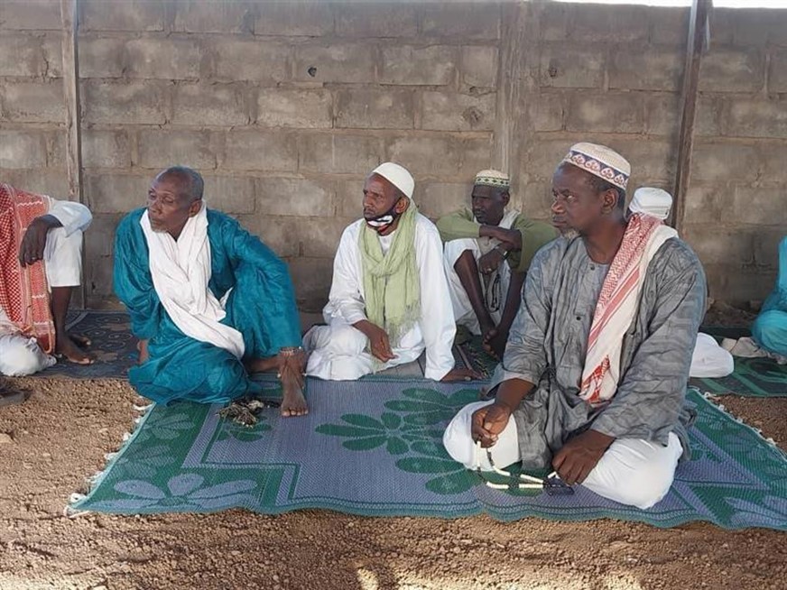 4 men listen while sitting on a rug.